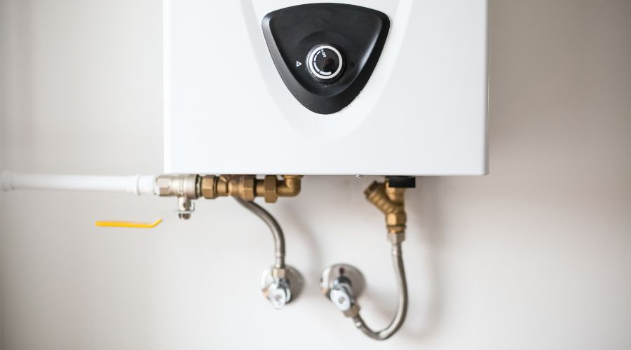 Compact white water heater with black control knob and visible plumbing connections for efficient home maintenance.